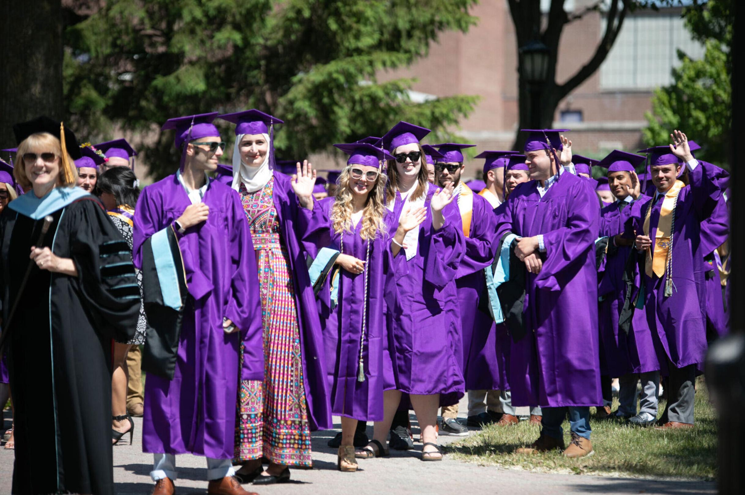 一群2023届毕业生在毕业典礼上对着镜头挥手